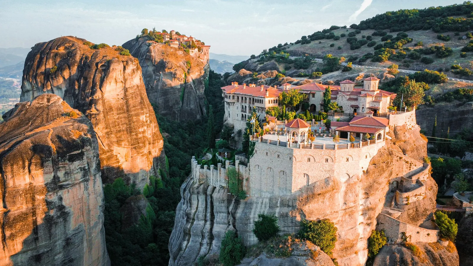 The Holy Monastery of Varlaam perched on a sandstone pillar at golden hour in Meteora, Greece